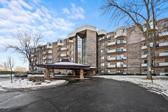 Front view of a multi-story residential building with balconies and a covered entrance.