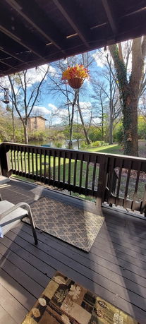 View of a backyard deck with railing overlooking a grassy area and trees.