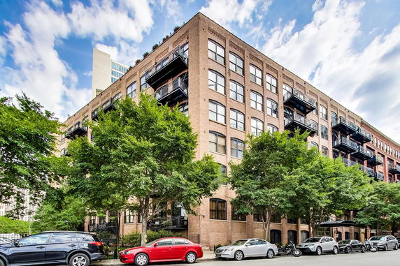 Front view of a multi-story brick building with balconies and large windows.