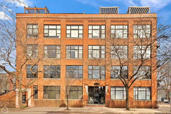 Front view of a multi-story brick building with large windows.