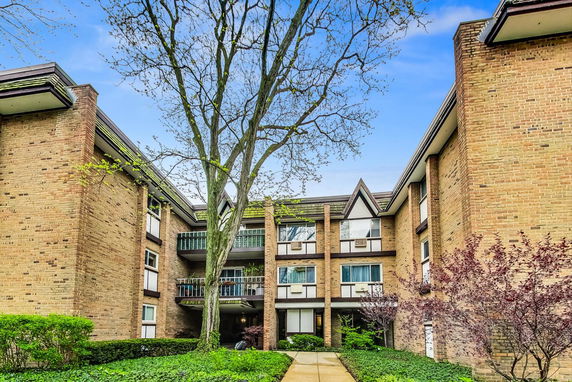 Front view of a multi-story brick apartment building with balconies.
