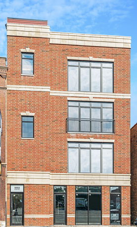 Front view of a three-story brick building with large windows.