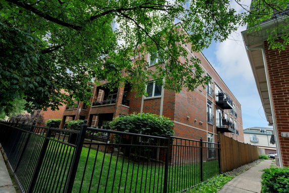 Front view of a multi-story brick apartment building with balconies.