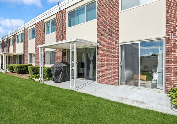 Front view of a two-story brick building with multiple windows and sliding glass doors.