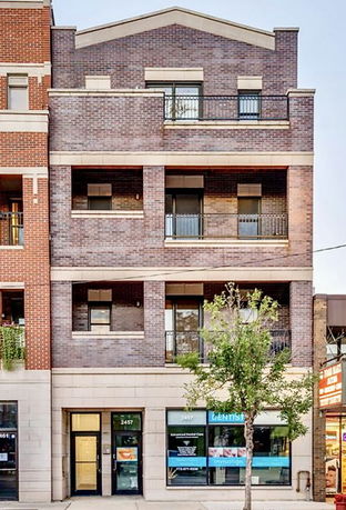 Front view of a multi-story brick building with balconies.