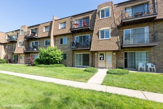 Front view of a multi-story residential building with balconies and brick exterior.