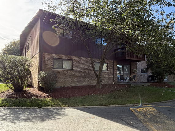 Side view of a two-story house with brick and wood exterior.