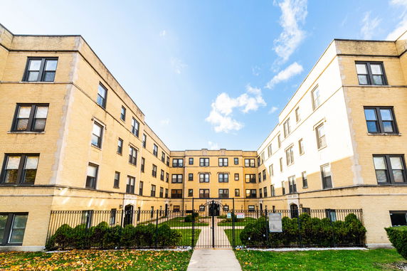 Front view of a multi-story apartment building with yellow brick facade.