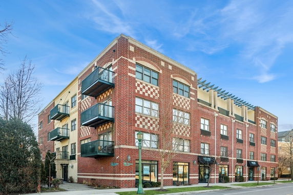 Front view of a multi-story brick building with balconies and large windows.