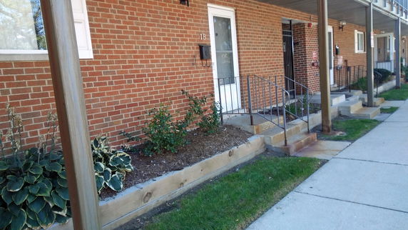 Front view of a brick residential building with stairs leading to the entrance.