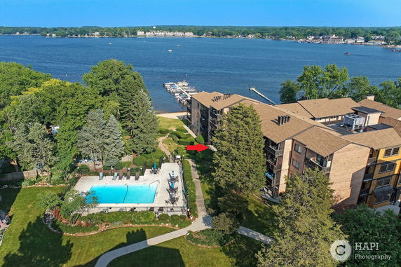 Panoramic view of a multi-story building complex with a swimming pool and lake in the background.