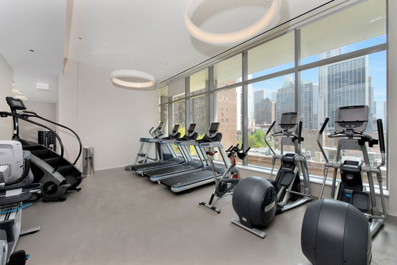 Interior view of a gym with exercise equipment and large windows.