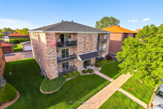Front view of a three-story brick apartment building with balconies.