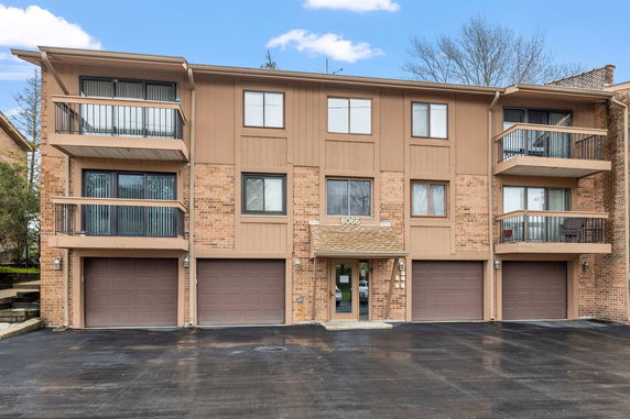 Front view of a three-story apartment building with balconies and garages.