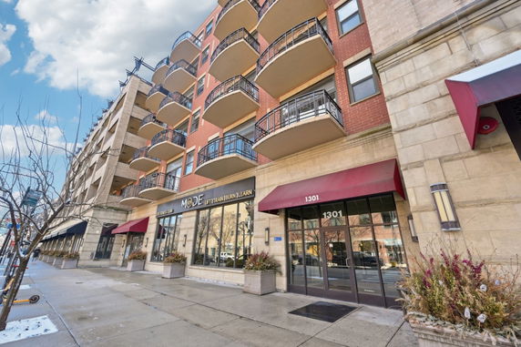 Front view of a multi-story building with balconies and storefronts on the ground level.