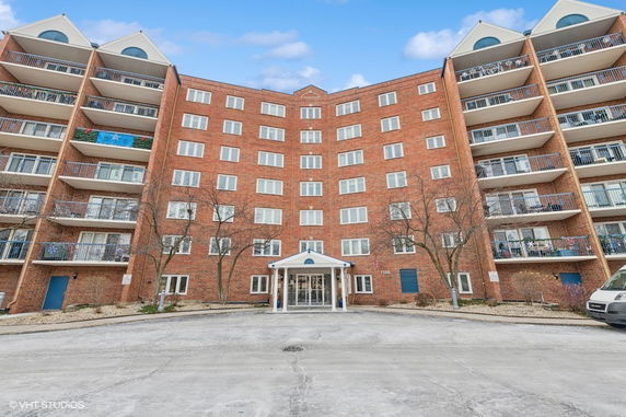 Front view of a multi-story brick apartment building with balconies.