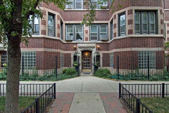Front view of a multi-story brick building with a gated entrance.