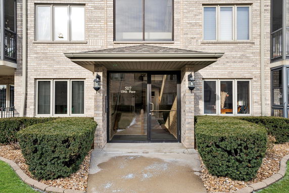 Front view of a multi-story building entrance with glass doors and brick exterior.