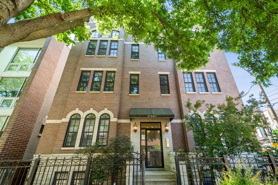 Front view of a multi-story brick building with large windows.