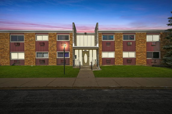 Front view of a two-story brick apartment building with a central entrance and symmetrical windows.