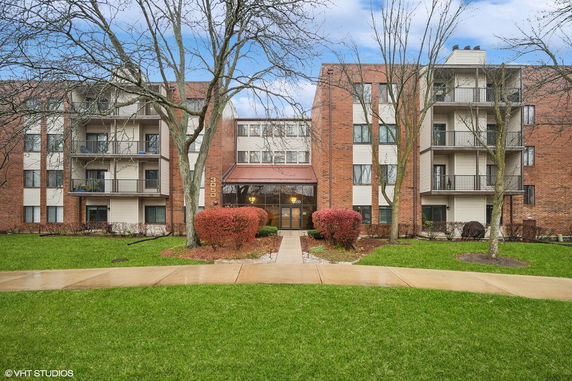 Front view of a multi-story residential building with balconies and a central entrance.
