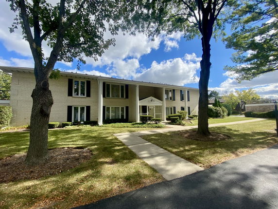 Front view of a two-story building with dark shutters and columns.