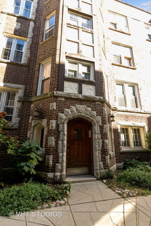 Front view of a brick building with detailed stonework around a wooden door.