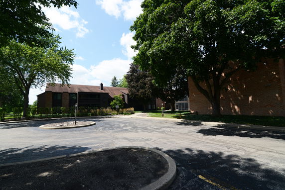 Front view of a two-story building with a gable roof and surrounding trees.