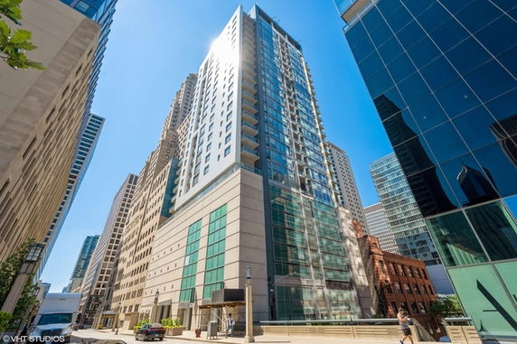 Front view of a tall modern building with glass windows in an urban setting.