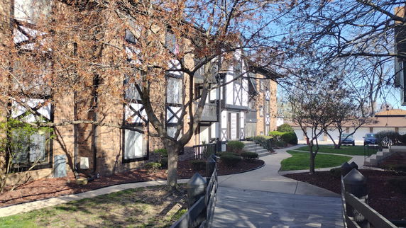 Front view of a multi-story apartment building with brick and wooden accents.