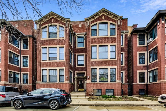 Front view of a three-story brick apartment building with multiple windows.