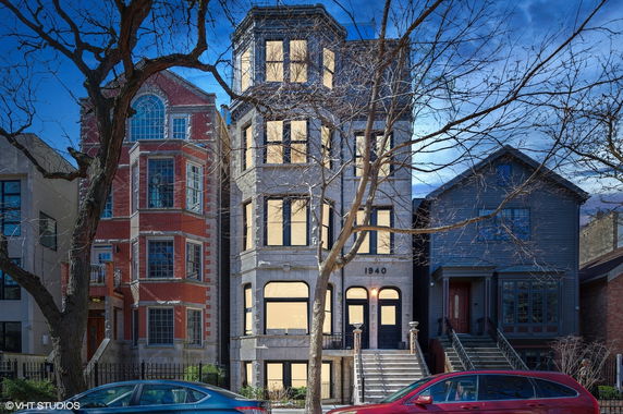 Front view of a multi-story residential building with distinct architectural design, alongside similar structures.