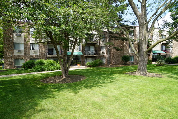 Front view of a multi-story apartment building with brick exterior and balconies.