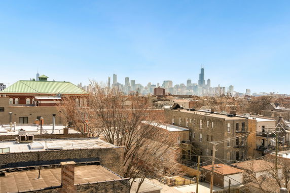 Panoramic view of a cityscape with high-rise buildings in the background and residential buildings in the foreground.