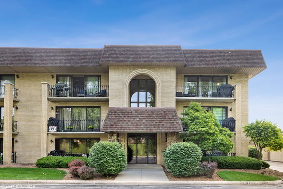 Front view of a multi-story residential building with balconies and an arched entrance.