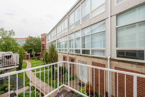 Back view of a modern building with large glass windows and a garden path.