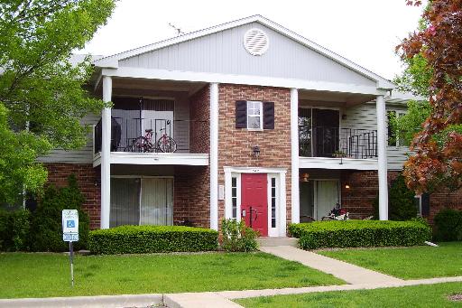Front view of a two-story building with balconies and a red front door.