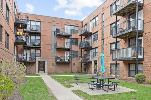 View of a multi-story brick apartment building with balconies.