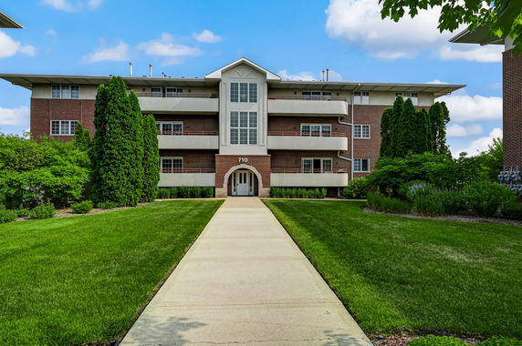 Front view of a multi-story residential building with a brick facade and balconies.