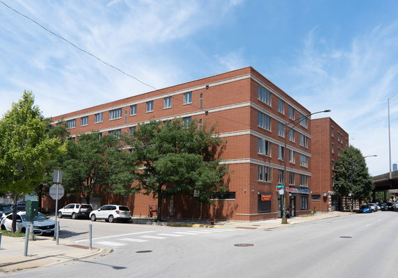 Front view of a multi-story brick building with large windows.