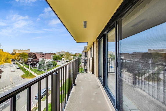 View from a balcony overlooking a street and buildings in an urban area.