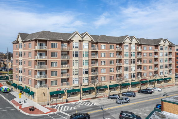 Front view of a multi-story apartment building with commercial spaces on the ground floor.
