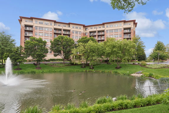 Front view of a multi-story residential building with a pond and fountain.