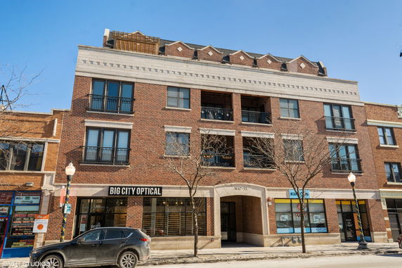 Front view of a multi-story brick building with ground-floor retail stores.