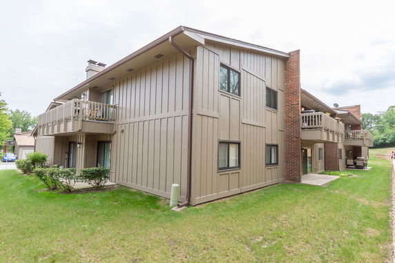 Front view of a multi-story residential building with beige paneling and balconies.