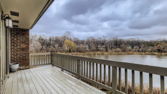 View from a deck overlooking a river and distant trees.