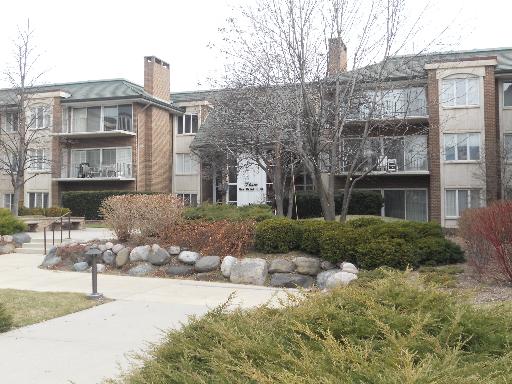 Front view of a multi-story apartment building with balconies and a green roof.