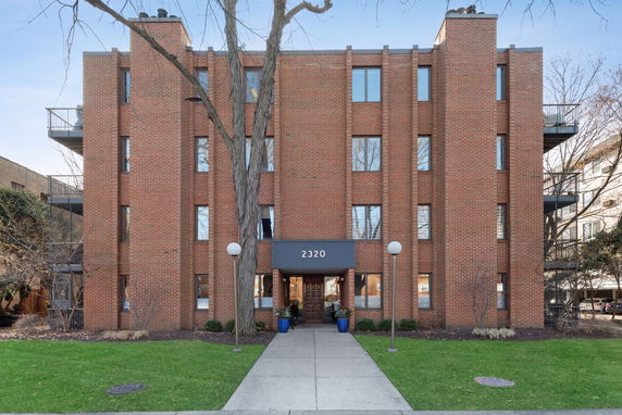 Front view of a four-story brick building with balconies and a central entrance labeled 2320.
