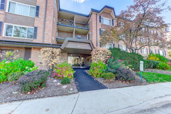 Front view of a multi-story brick building with balconies and a walkway leading to the entrance.