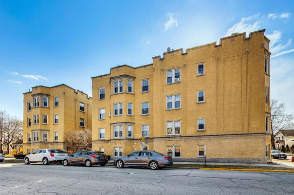 Front view of a multi-story yellow brick apartment building.
